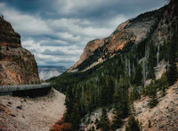 a road in the middle of a canyon under a cloudy sky