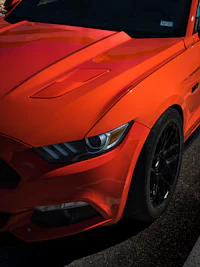 an orange ford mustang parked on the side of the road