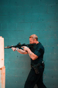 a man holding a gun in front of a blue wall